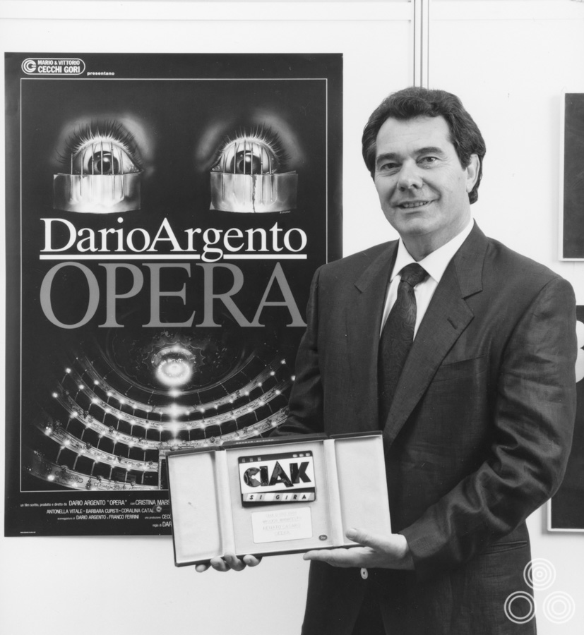 Renato Casaro stands proudly holding the Ciak D'Oro advertising award which he won for the Italian poster for Dario Argento's Opera, 1987.