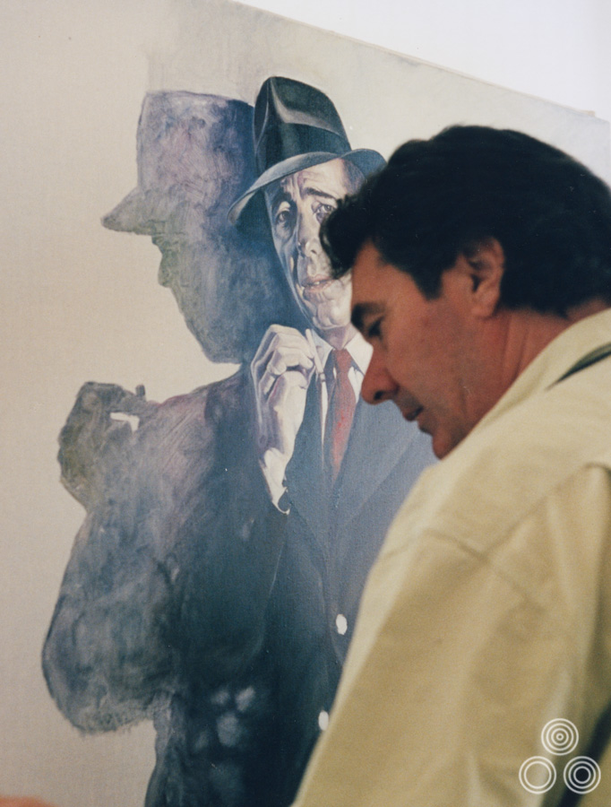 Renato Casaro works on a portrait of Humphrey Bogart in The Maltese Falcon as part of his Painted Movies series, 1992. For more examples from the series click here.